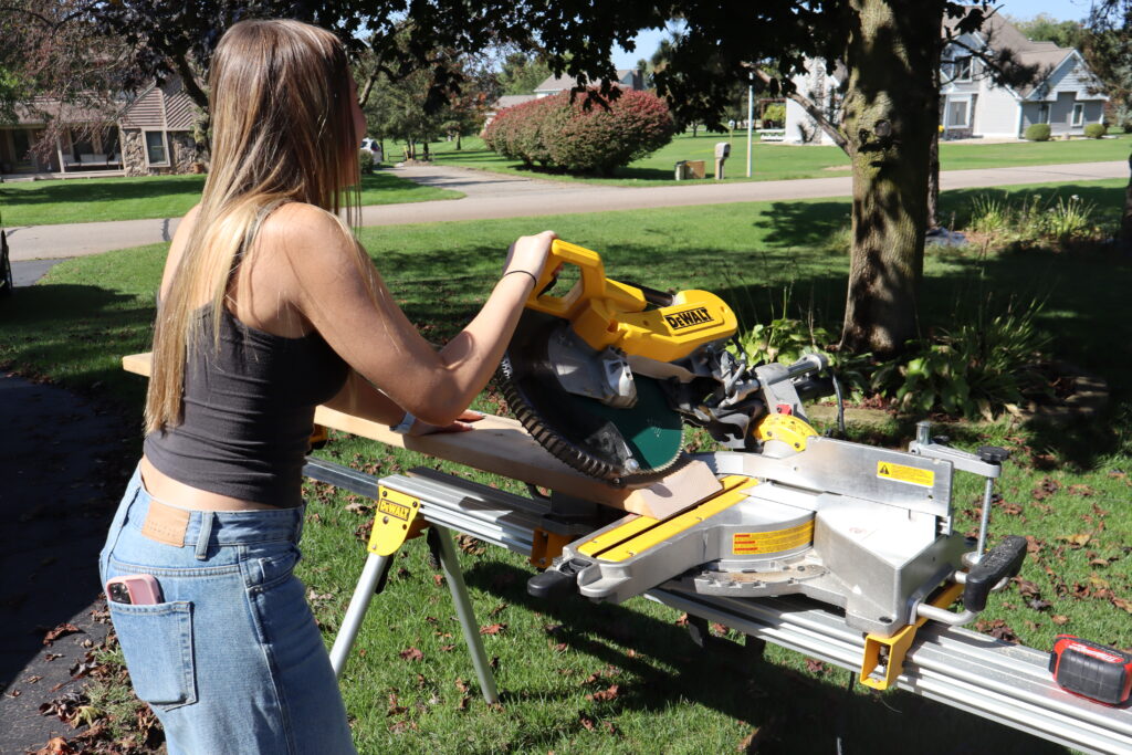 Using a Miter saw to cut wood to create the pumpkin shape.