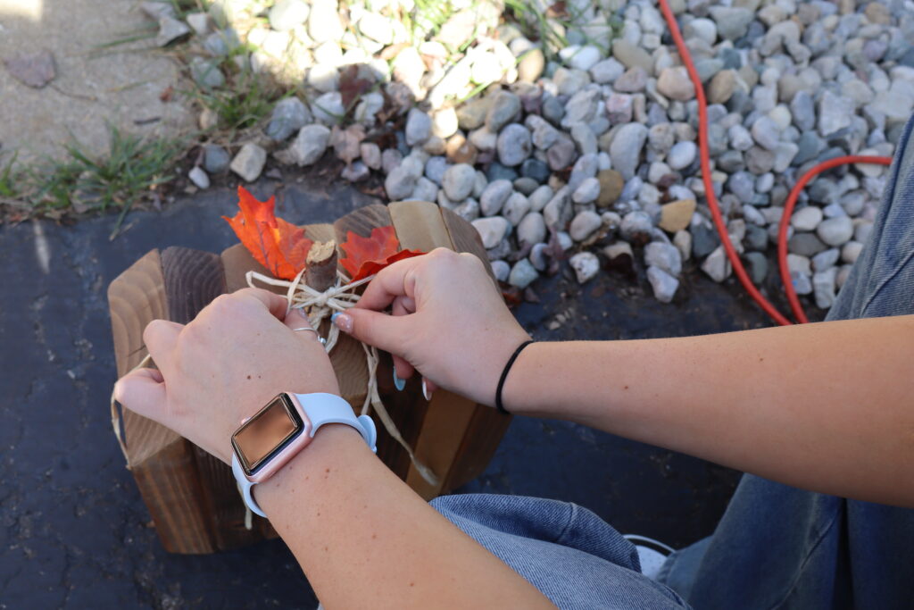 Tying twine around the stick (pumpkin stem).